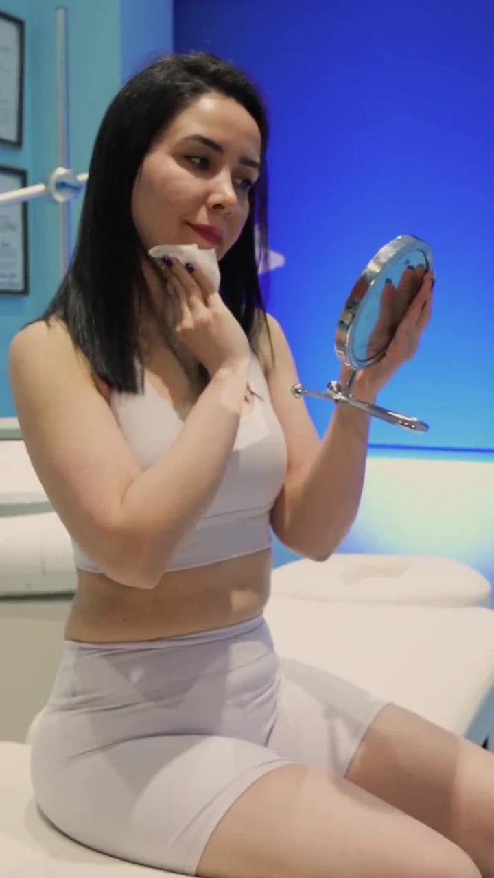 Client checking her skin in a hand mirror after treatment
